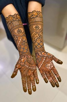 two hands with henna tattoos on them, one is showing the intricate pattern and the other