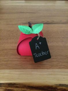 a red apple with a green leaf and a teacher's tag attached to it