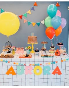 a table topped with lots of cake and balloons