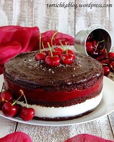 a chocolate cake topped with cherries on top of a white plate