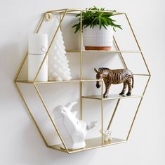 a gold hexagonal shelf with two zebra figurines and a white ceramic animal