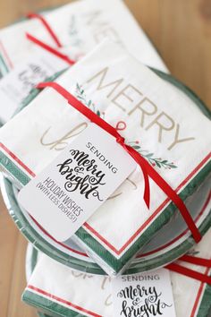 three christmas napkins wrapped in red and green ribbon on top of each other with a merry tag