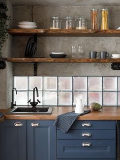 a kitchen with blue cabinets and wooden counter tops, open shelving above the sink