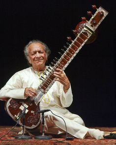 a man sitting on the ground playing an instrument