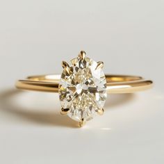 a yellow gold engagement ring with a round brilliant cut diamond in the center, on a white background