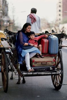 a woman and child are riding in a horse drawn carriage with luggage on the back