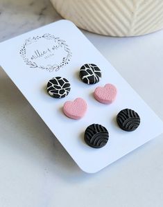 four black and pink heart shaped buttons sitting on a white plate next to a bowl