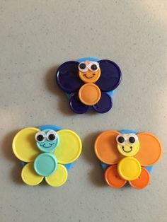 three different colored buttons with eyes and ears on top of a table next to each other