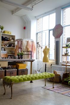 a room filled with lots of furniture next to a large window and a yellow bench