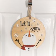 a wooden sign that says let it snow hanging on a door with an ornament