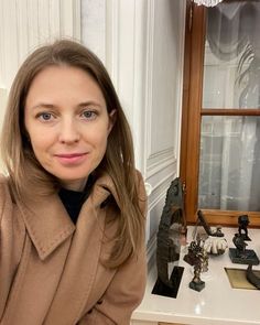 a woman standing in front of a mirror with her hands on her hips and looking at the camera