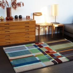 a living room area with a rug, couch and table in the background on hardwood flooring