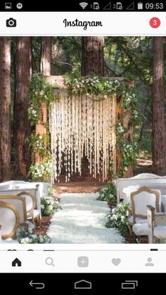 an outdoor ceremony in the woods with white flowers and greenery hanging from the trees