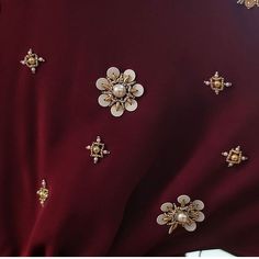 closeup of the back of a maroon dress with gold brooches on it