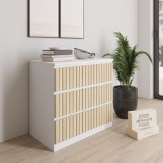 an empty room with a plant and two framed pictures on the wall next to it