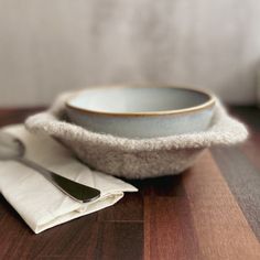 a bowl and spoon sitting on top of a wooden table next to a white napkin