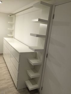 an empty room with white shelves and drawers