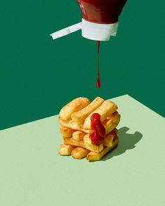 a pile of french fries with ketchup dripping from the top on green background