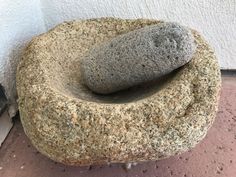 a rock sitting on the ground next to a wall