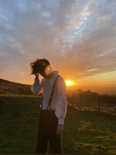 a man standing on top of a lush green field holding a cell phone to his ear