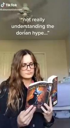 a woman is reading a book in front of a sign that reads, not really understanding the dorian hype