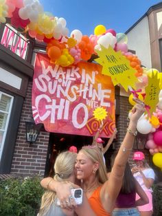 two women hugging each other in front of a building with balloons and stars on it