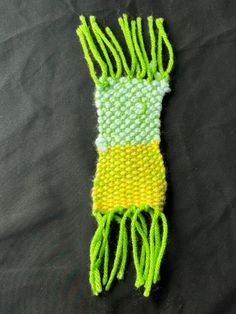 a green and yellow beaded object laying on top of a black cloth covered table