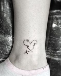 a small heart with an arrow tattoo on the side of the ankle is shown in black ink