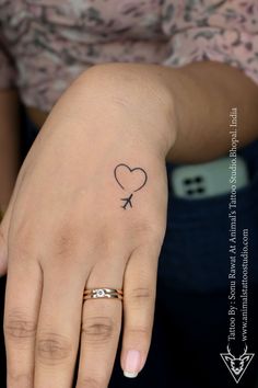 a woman's hand with a heart and an arrow tattoo on the middle finger