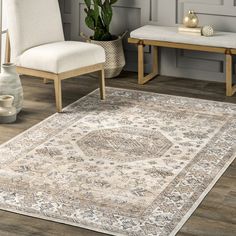 a large rug with an ornate design on the floor next to two chairs and a bench