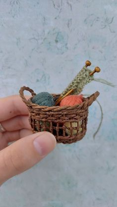 someone is holding a miniature basket with yarn in it