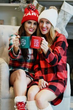 two women sitting on a couch holding mugs in front of christmas stockings and stockings