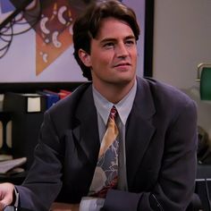 a man in a suit and tie sitting at a desk looking off into the distance