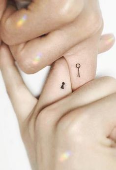 two hands holding each other with small tattoos on their thumbnails and one finger