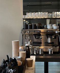 an espresso machine sitting next to stacks of coffee cups