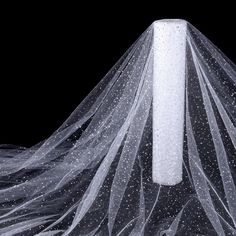 a veil with white dots on it sitting in front of a black background