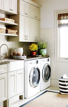 a washer and dryer in a small room next to a window with flowers