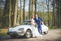 a bride and groom standing in front of an old car