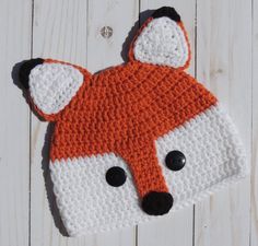 an orange and white knitted hat with a fox's head on top of it