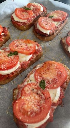 several slices of bread with tomatoes and mozzarella on them sitting on a baking sheet