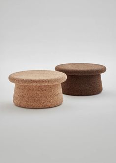 two small round stools sitting next to each other on a white surface and one is made out of cork