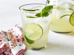 two glasses filled with lemonade and limeade on top of a table next to a napkin