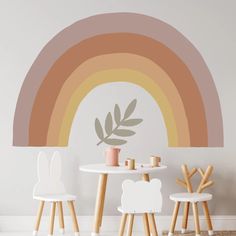 a white table and two chairs in front of a wall with a rainbow painted on it