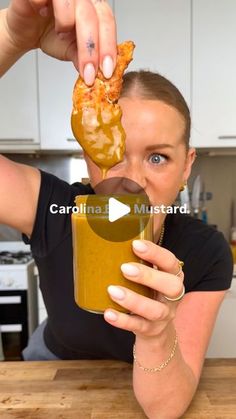 a woman is holding up a cup with food in it and she has her mouth open