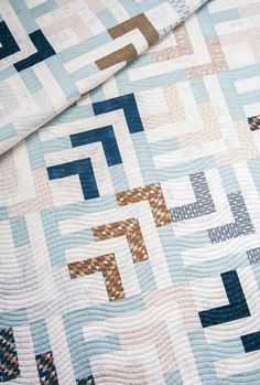 a blue and white quilt on top of a bed next to a pillow coverlet