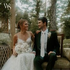 a bride and groom sitting on a bench in the woods