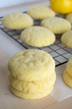 some cookies are cooling on a rack next to lemons and an orange in the background