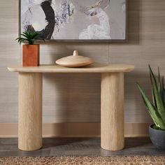 a wooden table with a potted plant on it in front of a large painting