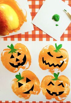 three pumpkins painted on paper next to an apple