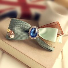 a book with a bow and brooch on it sitting on a table next to a flag